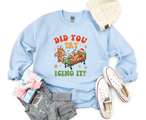 Did You Try Icing It?" holiday crewneck featuring a gingerbread man in a hospital scene with a gingerbread nurse, adding humor and festive cheer to a cozy winter sweater.