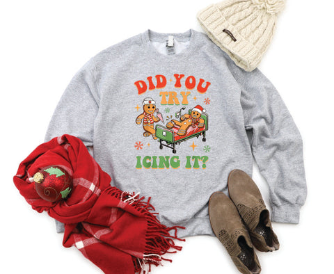 Did You Try Icing It?" holiday crewneck featuring a gingerbread man in a hospital scene with a gingerbread nurse, adding humor and festive cheer to a cozy winter sweater.